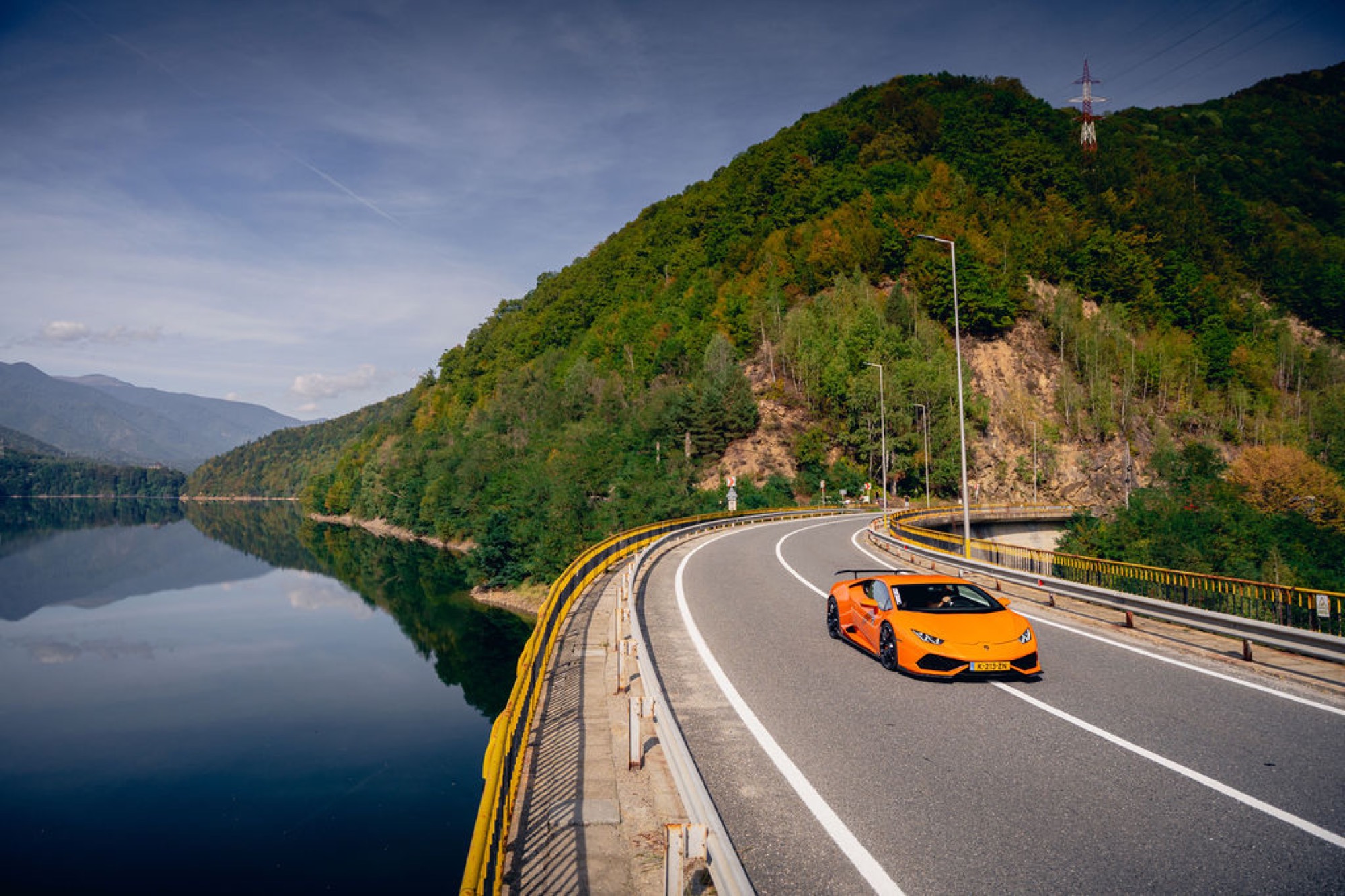 Supercar weerspiegelt in een bergmeer onderweg.